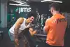 Personal trainer die uitleg geeft aan klant die biceps curl doet met een dumbell
